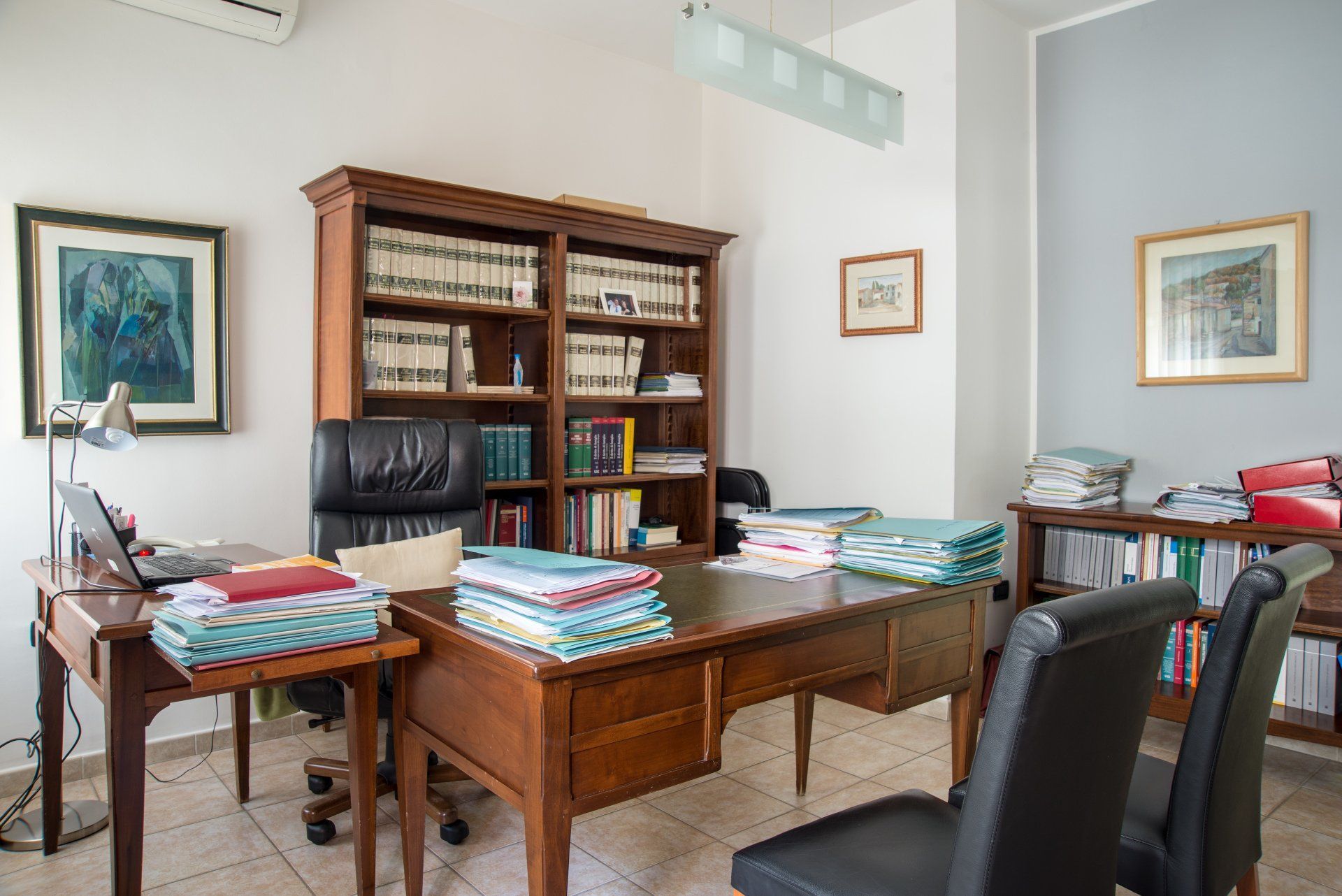 Una stanza con una scrivania, sedie, librerie e un computer.