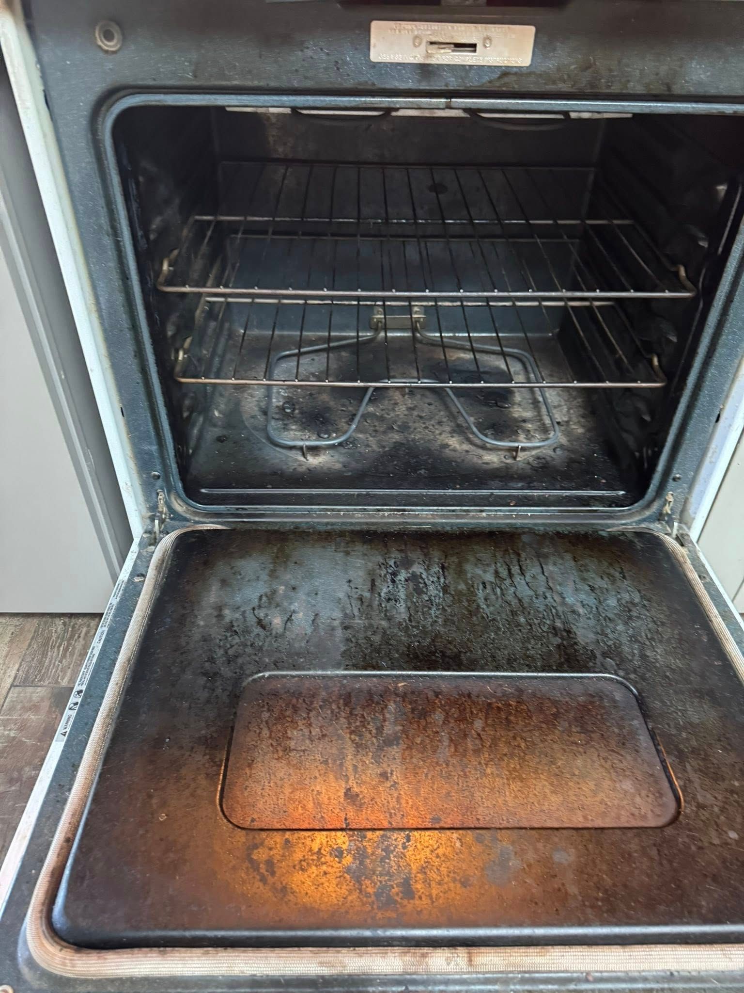 Dirty oven interior with racks and a heavily soiled bottom panel.