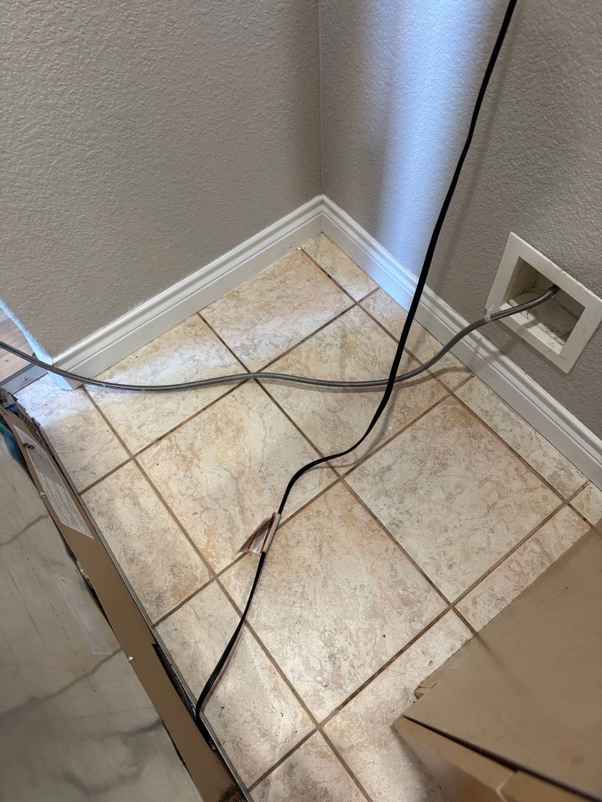 Electrical cords crossing tiled floor, near wall and vent.