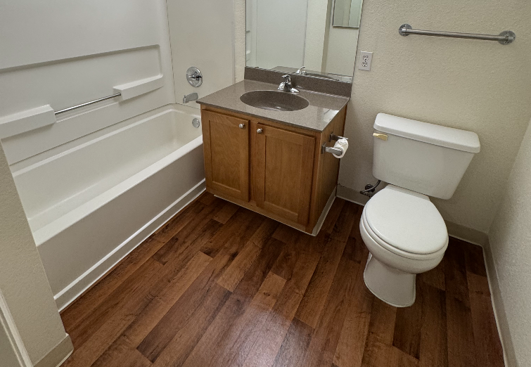 Open beige toilet with lid up, set on tiled floor.