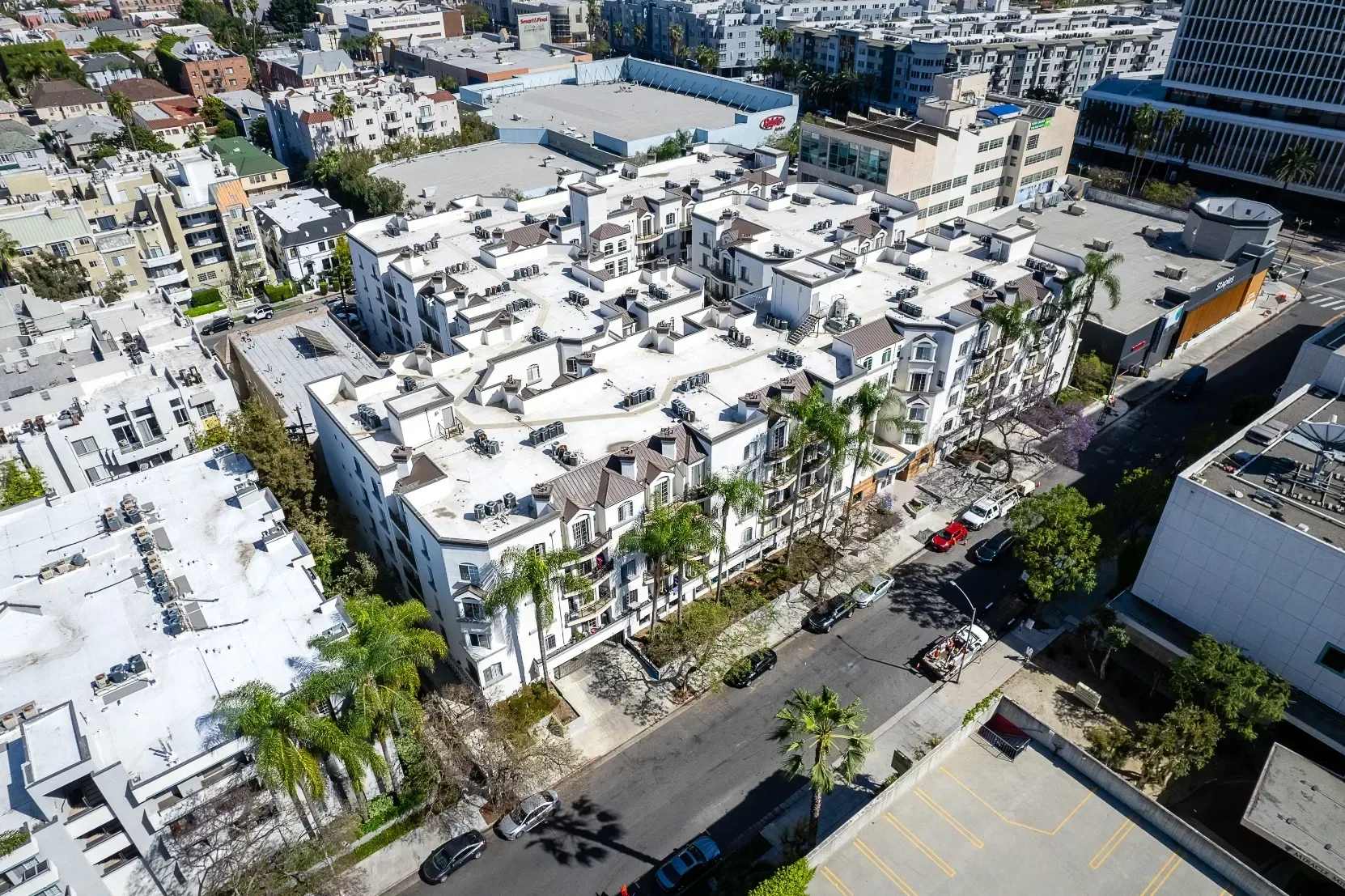 Aerial view of a large apartment building with palm trees and surrounding urban cityscape at The Preston in Los Angeles, CA.