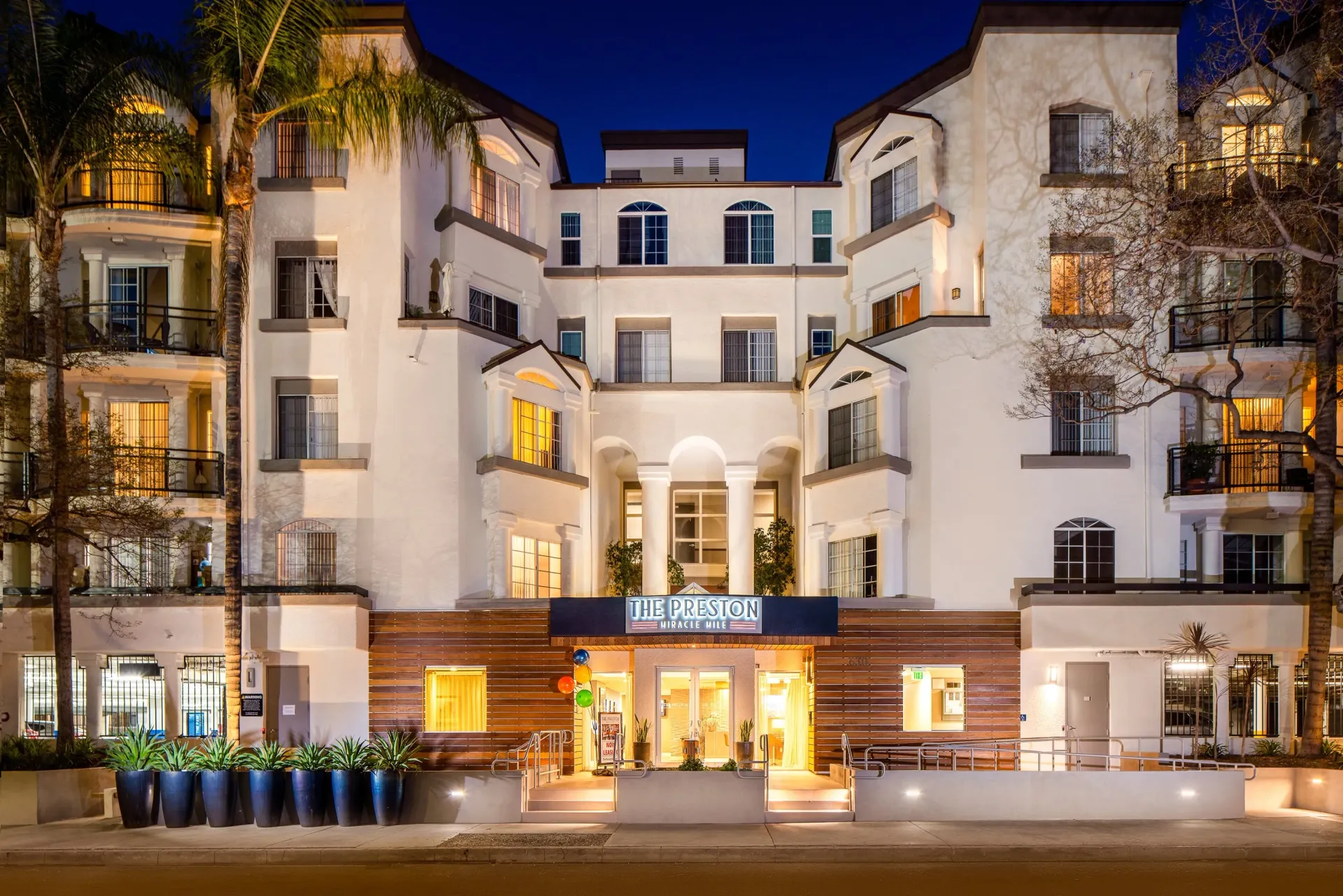 The Preston apartment building exterior at night, with illuminated windows and entrance in Los Angeles, CA.