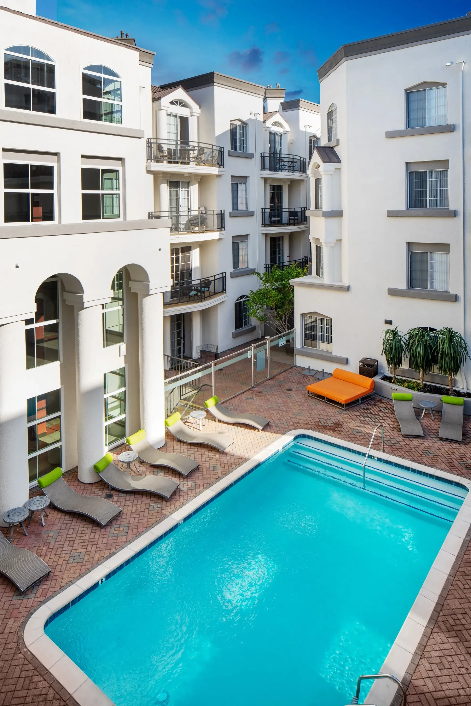 Outdoor swimming pool with lounge chairs and apartment buildings in the background at The Preston in Los Angeles, CA.