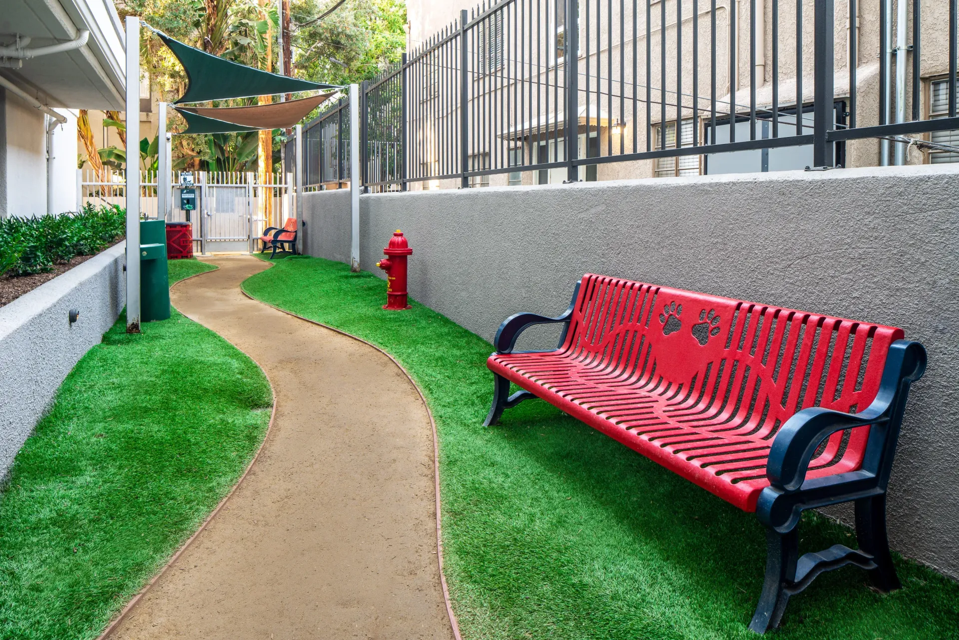 Dog park area with a red bench, fire hydrant, and walking path at The Preston in Los Angeles, CA.