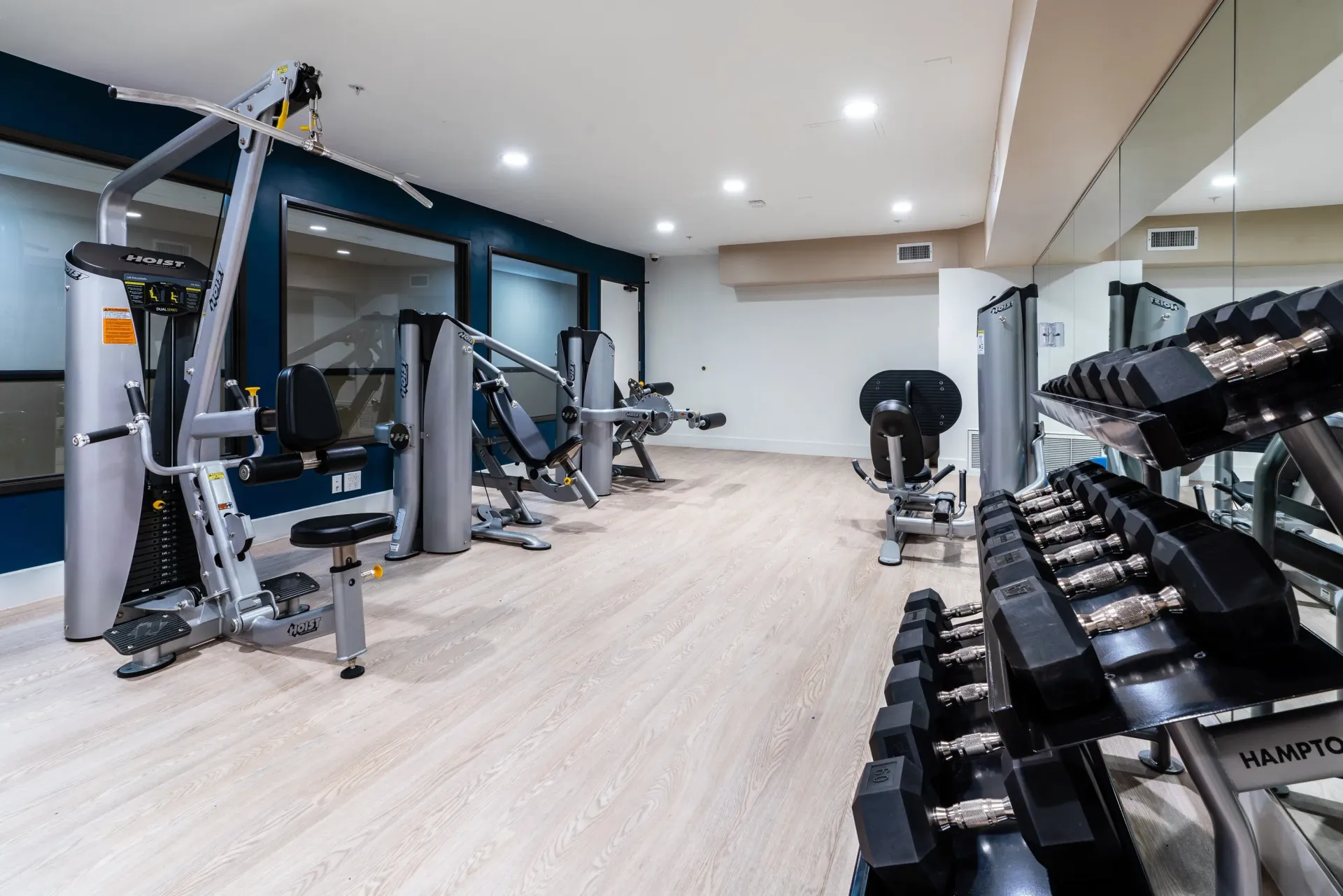 Fully equipped gym with weight machines and dumbbells at The Preston in Los Angeles, CA.