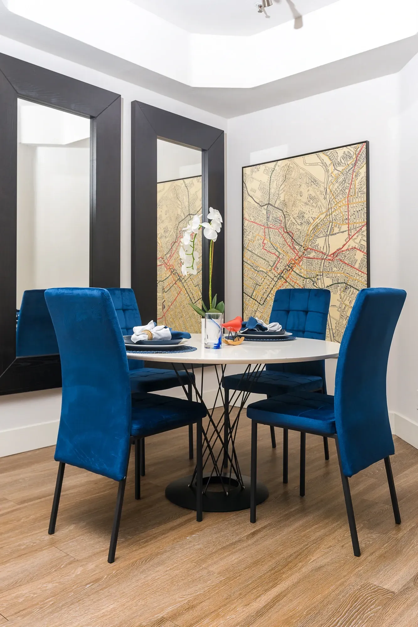 Dining area with a round table and four blue chairs, set for a meal at The Preston in Los Angeles, CA.