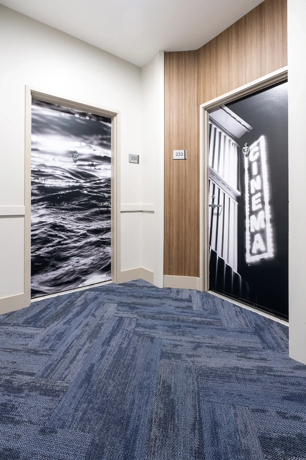 Hallway with two doors, one with a wave graphic and one with a cinema sign graphic at The Preston in Los Angeles, CA.