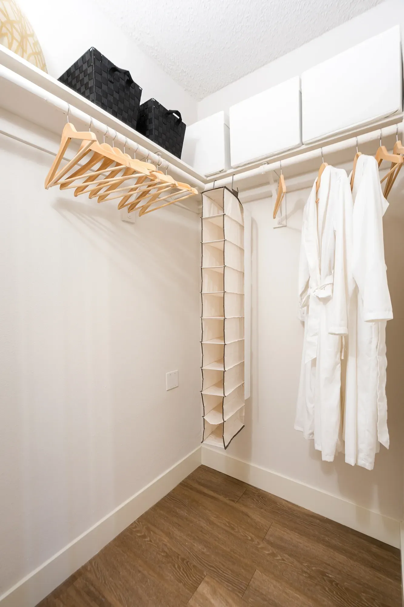 Walk-in closet with hanging clothes and a shoe organizer at The Preston in Los Angeles, CA.