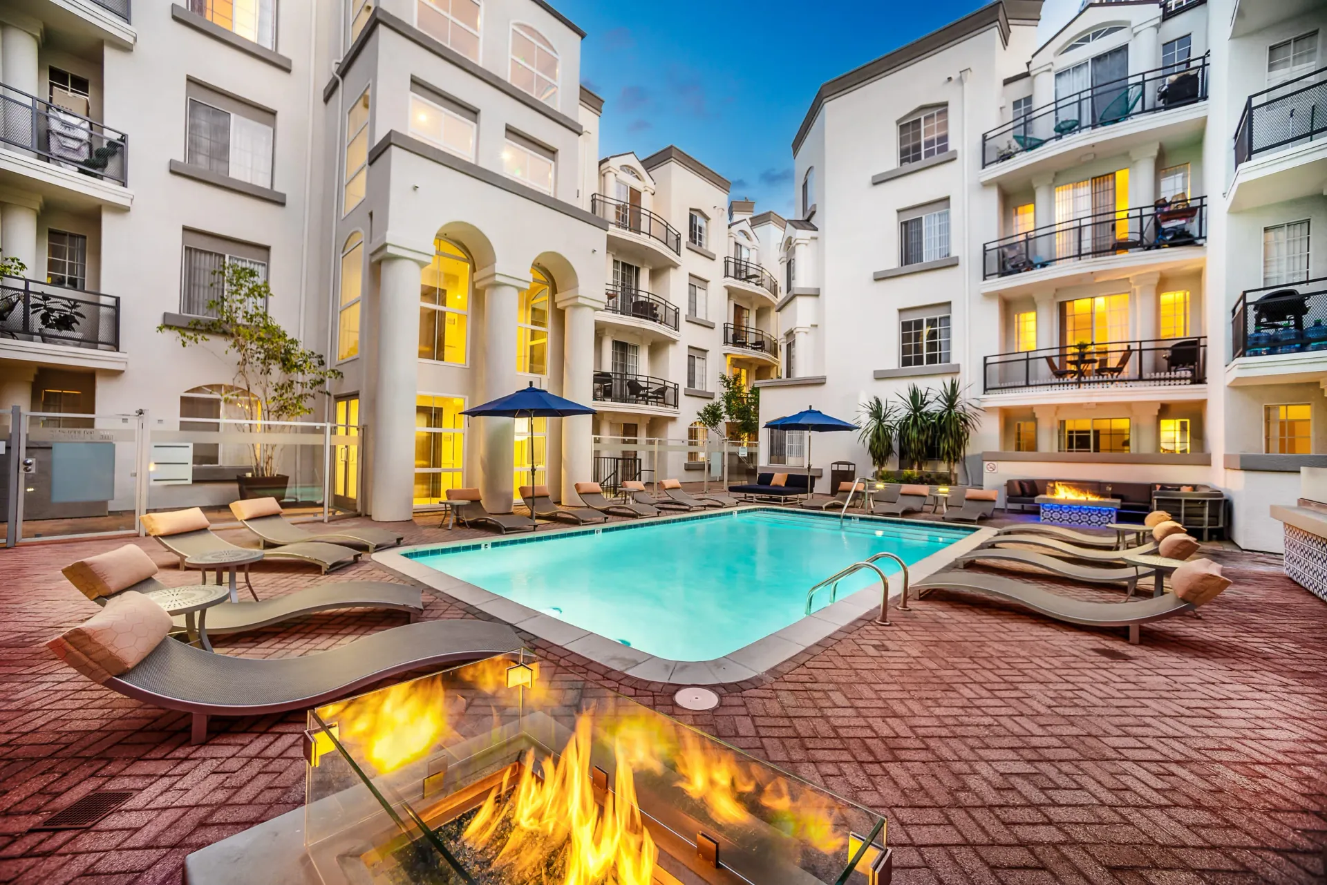 Courtyard pool and fire pit area with lounge chairs at the apartment complex at The Preston in Los Angeles, CA.