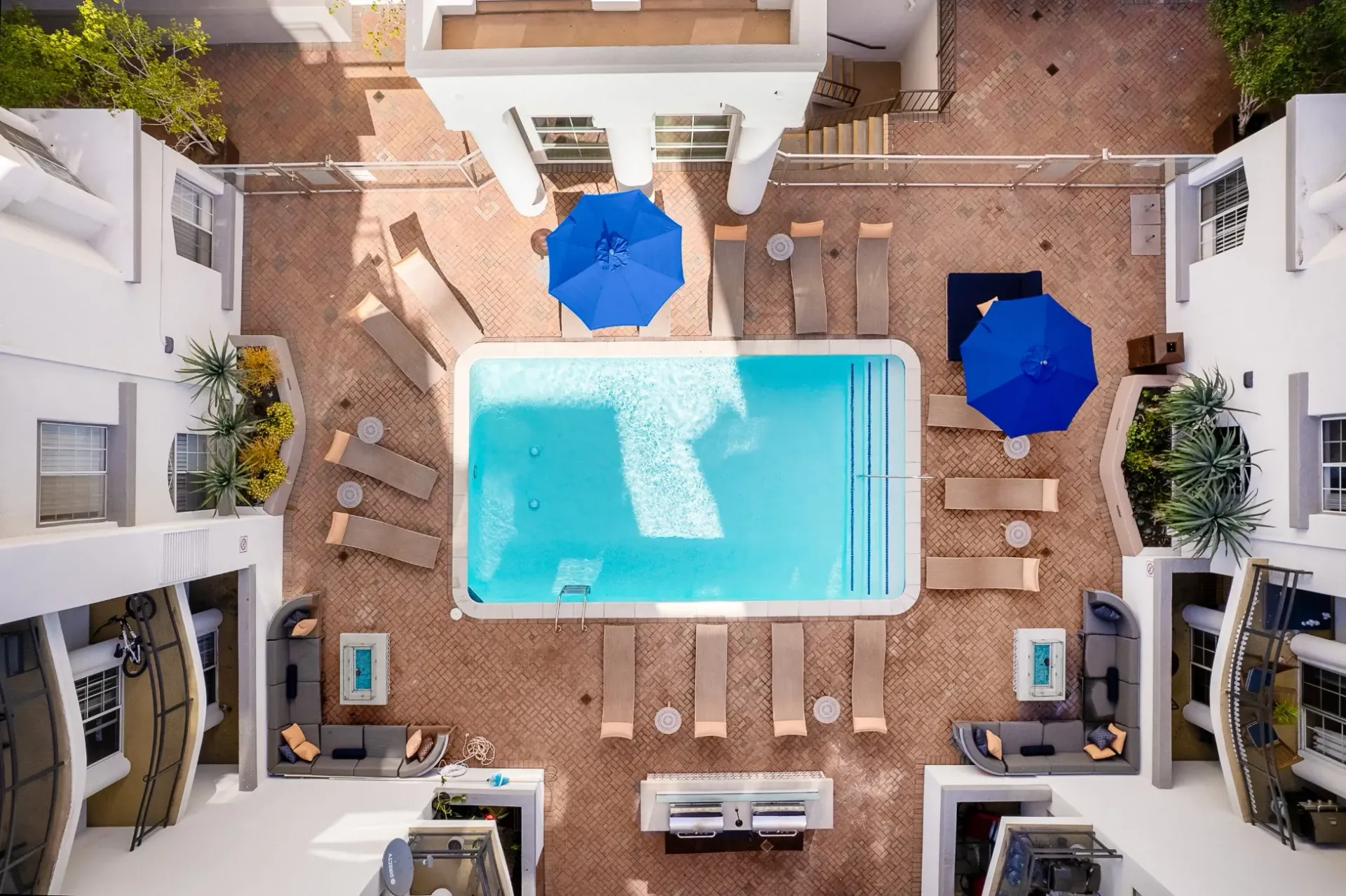 Aerial view of an outdoor swimming pool area with lounge chairs and umbrellas at The Preston in Los Angeles, CA.