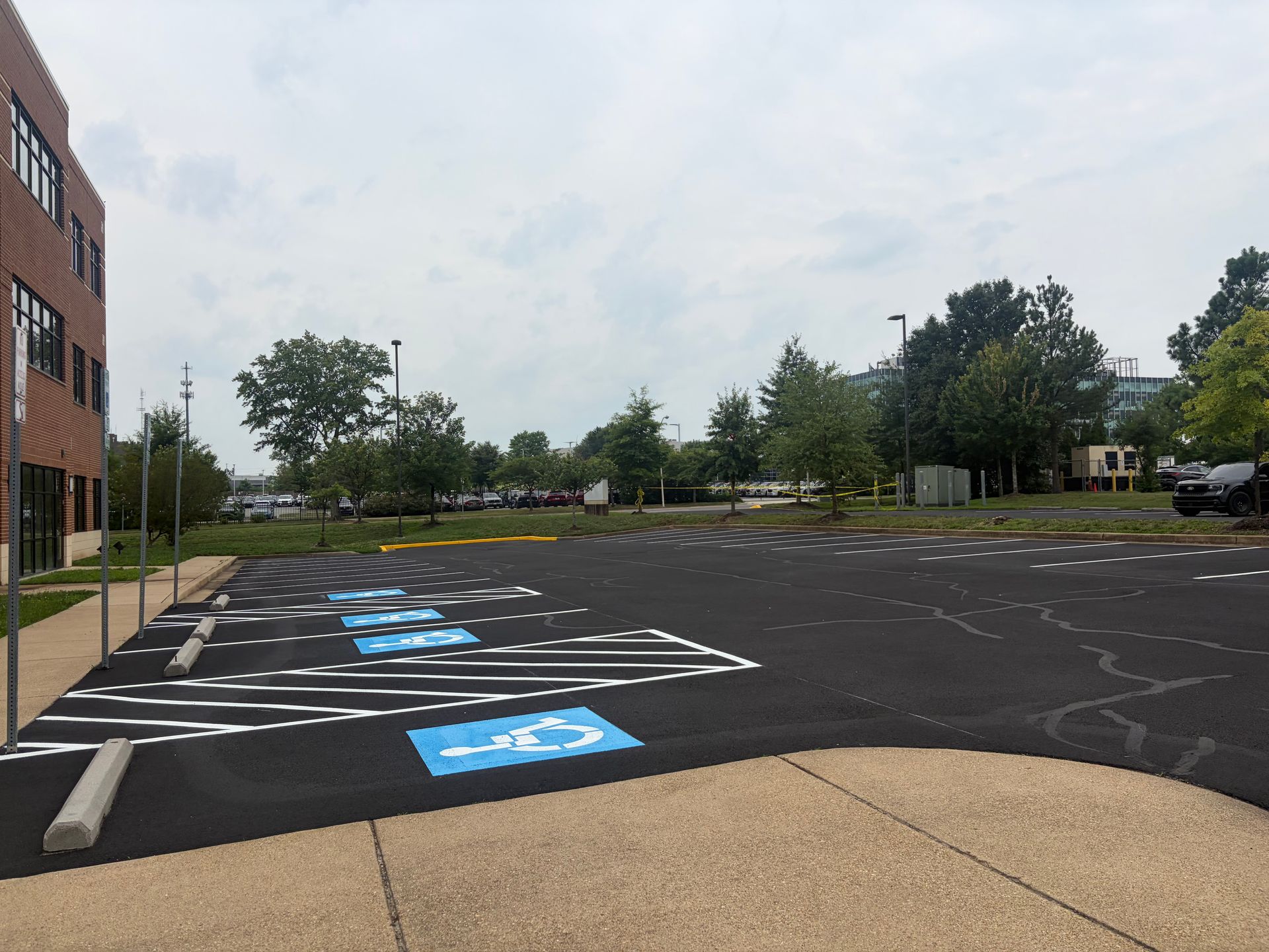 Empty accessible parking lot outside a brick building, with blue handicap spaces marked on the pavement.