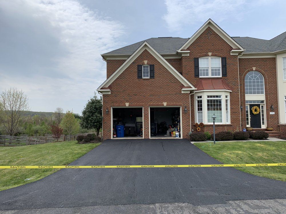 Two-story brick house with attached garage and driveway, yellow caution tape across the front lawn.
