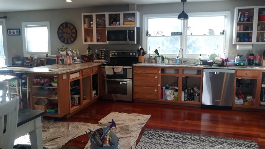 Kitchen undergoing renovation; cabinets and drawers are open. Brown wood floors and granite countertops.
