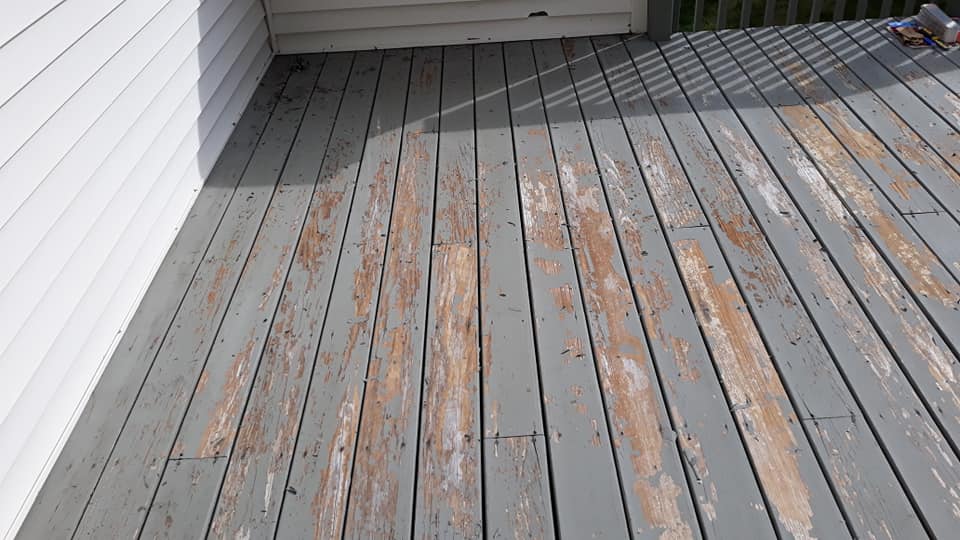 A wooden deck with peeling paint and a white house in the background.