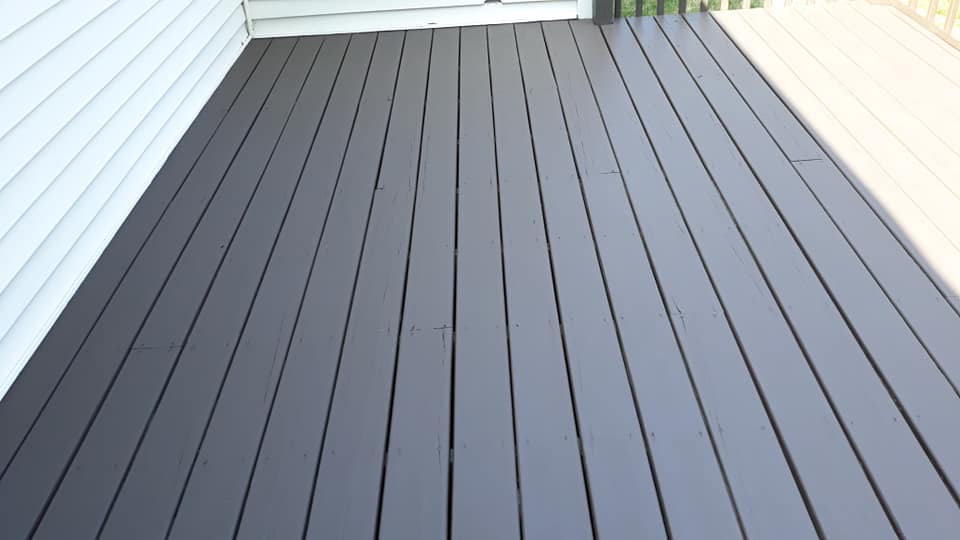 a black wooden deck with a white house in the background.