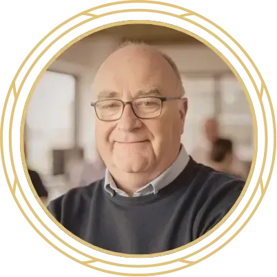 Smiling man in glasses in a circular gold frame, seated in a bright indoor setting