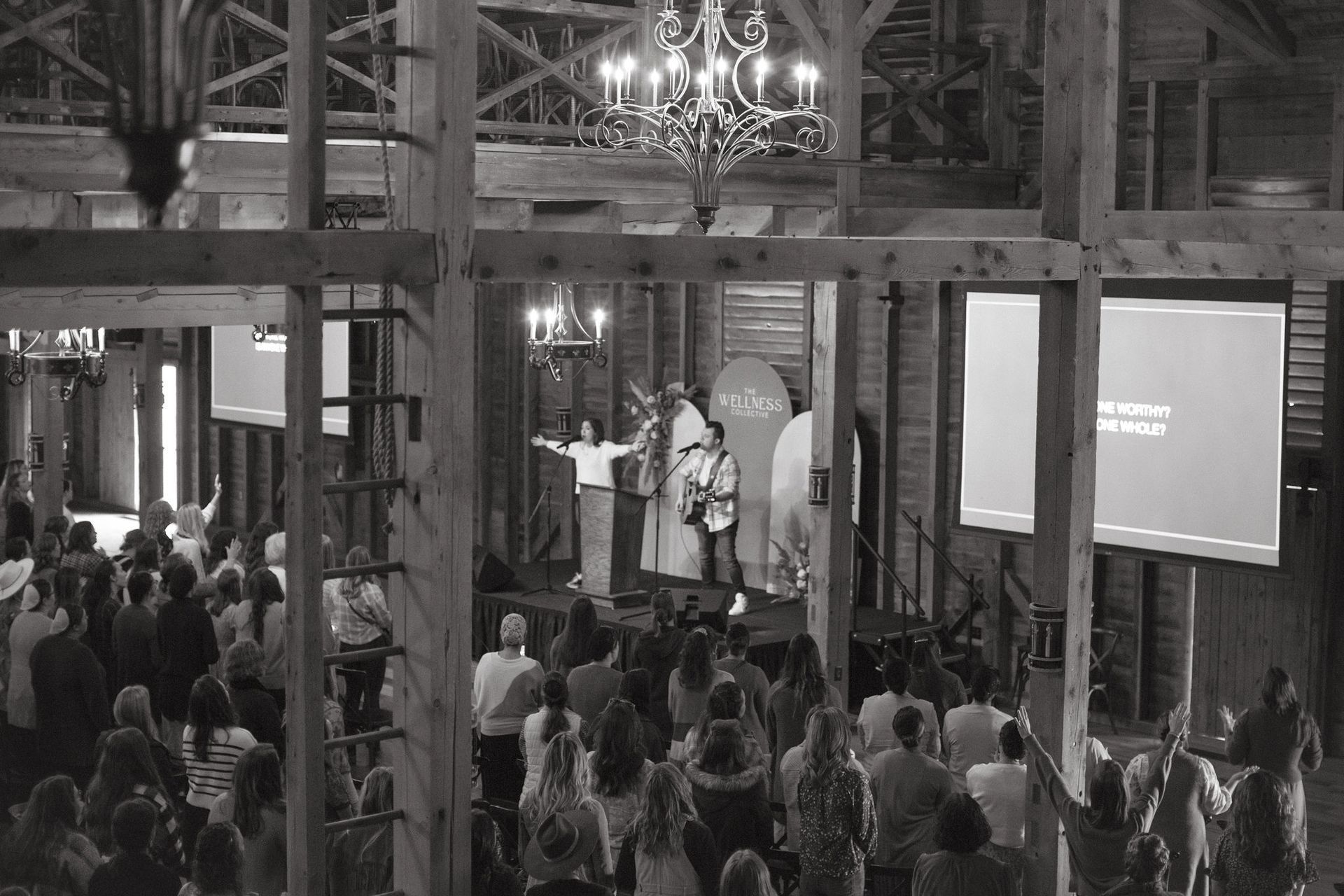 A black and white photo of a large group of people in a barn.