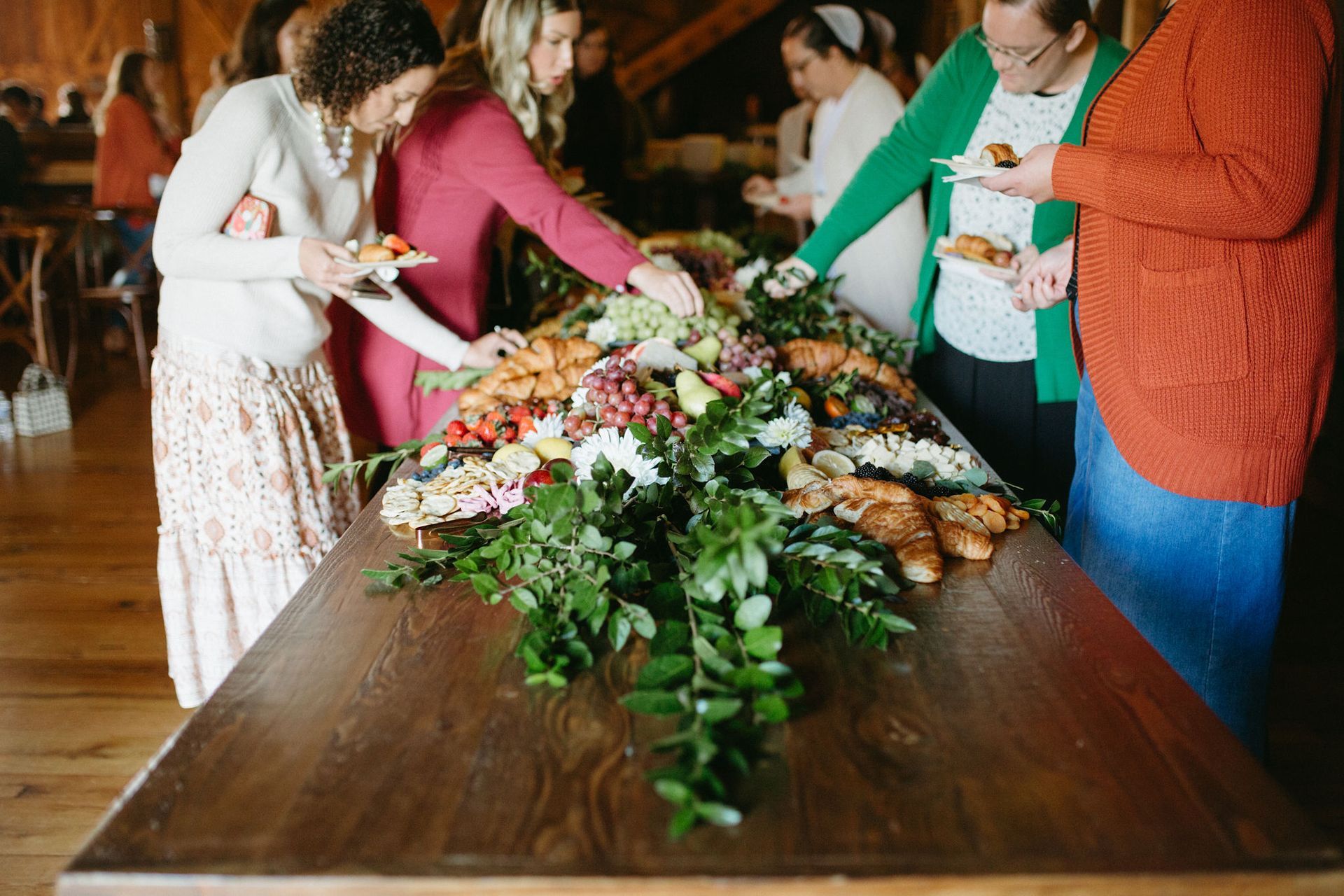 A group of women are standing around a table eating food.