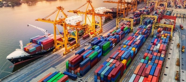 Un gran barco portacontenedores está atracado en un puerto lleno de muchos contenedores.