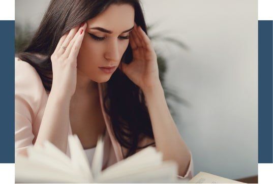 Una mujer sostiene su cabeza mientras lee un libro.