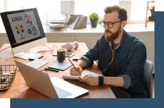 Un hombre está sentado en un escritorio con una computadora portátil y una computadora.