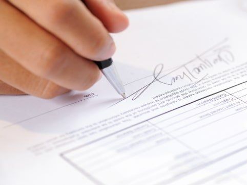 Un primer plano de una persona firmando un documento con un bolígrafo.