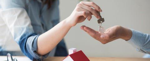 Una mujer le entrega una llave a un hombre frente a una casa modelo.