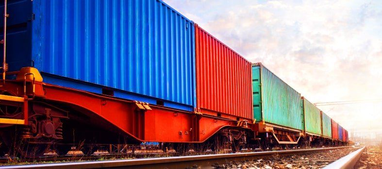 Un tren lleno de contenedores de colores va bajando por las vías.