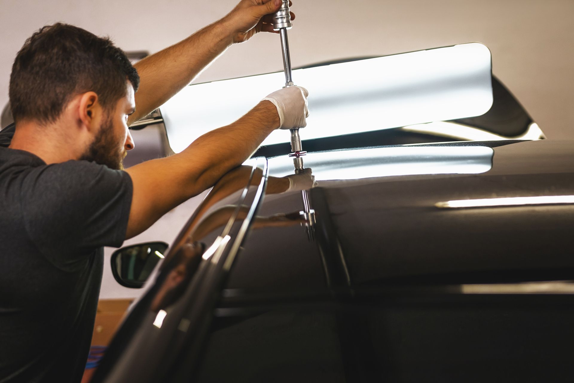 A man is working on the roof of a car.