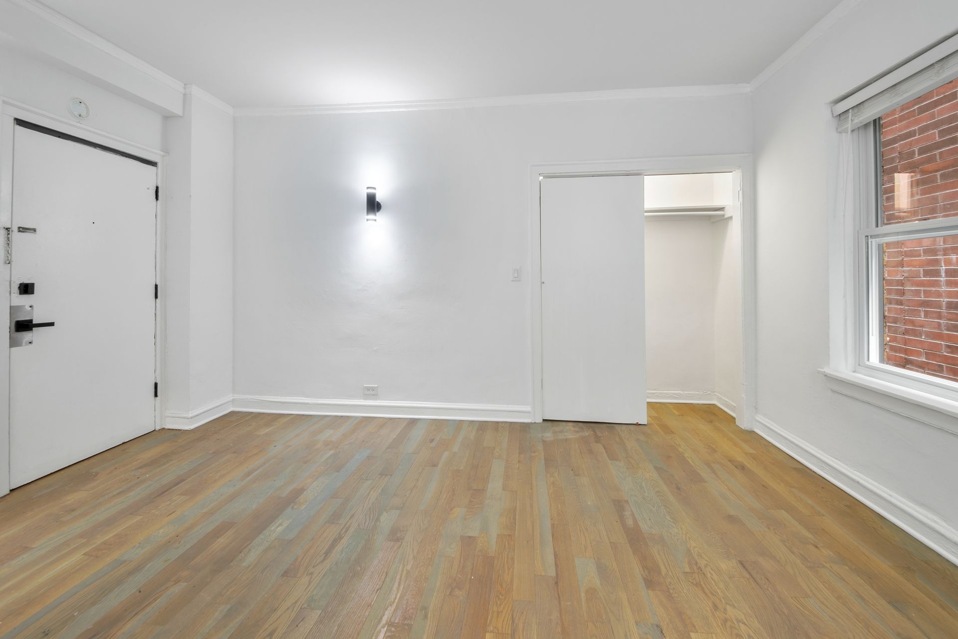 Empty room with hardwood floors, white walls, and a doorway.