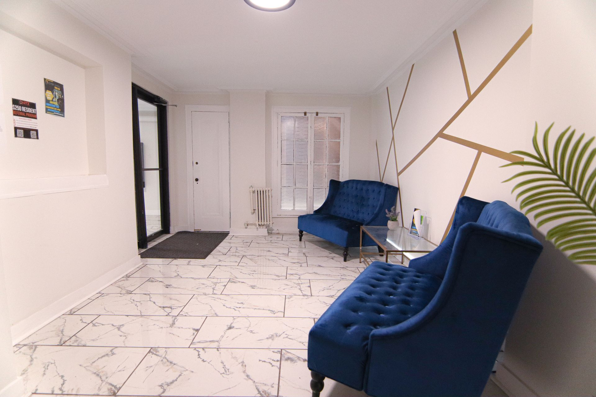 Elegant waiting room with blue velvet seating, marble floors, and gold wall art.