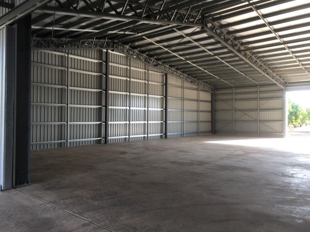 A Large Empty Warehouse With A Concrete Floor And A Metal Roof — SLS Builders Pty Ltd in Humpty Doo, NT