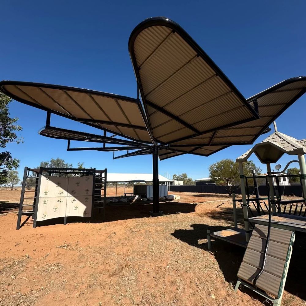 A Large Butterfly Shaped Umbrella Is In The Middle Of A Dirt Field — SLS Builders Pty Ltd in Humpty Doo, NT