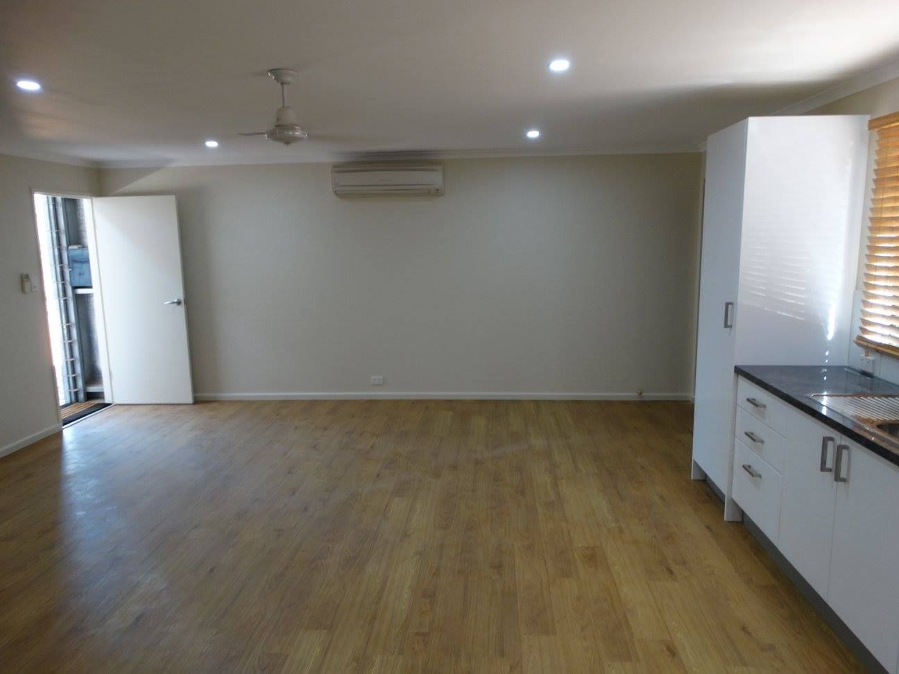 An Empty Room With Hardwood Floors And White Cabinets — SLS Builders Pty Ltd in Palmerston, NT