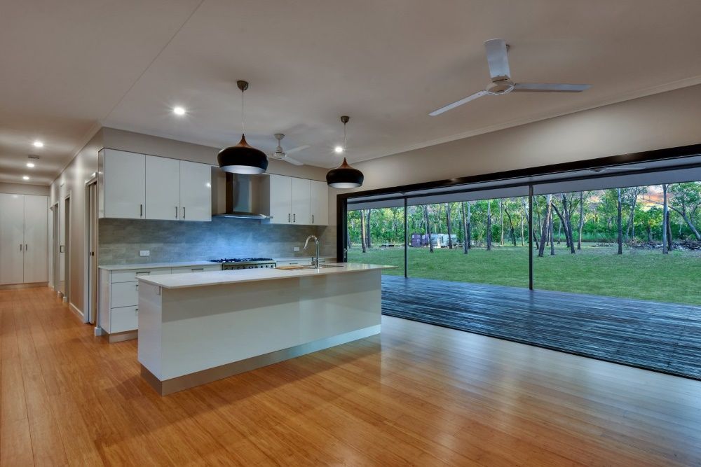 An Empty Kitchen With A Large Island And A Ceiling Fan — SLS Builders Pty Ltd in Yarralin, NT
