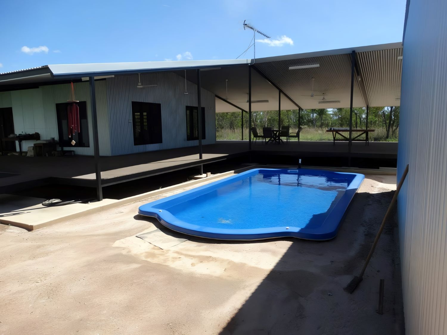 A Large Blue Swimming Pool in Front of a House — SLS Builders Pty Ltd in Humpty Doo, NT