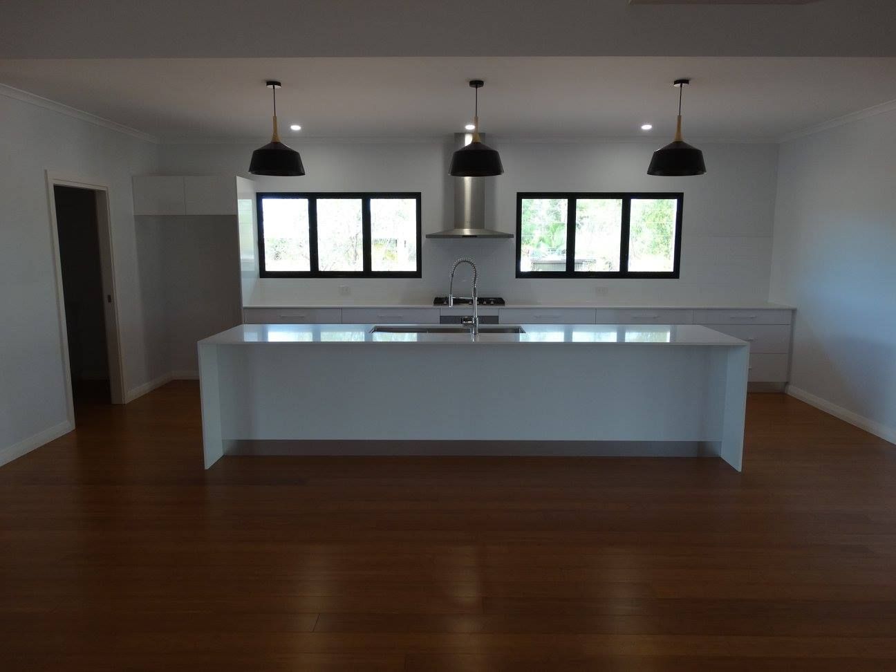 An Empty Kitchen With a Large Island in the Middle — SLS Builders Pty Ltd in Humpty Doo, NT