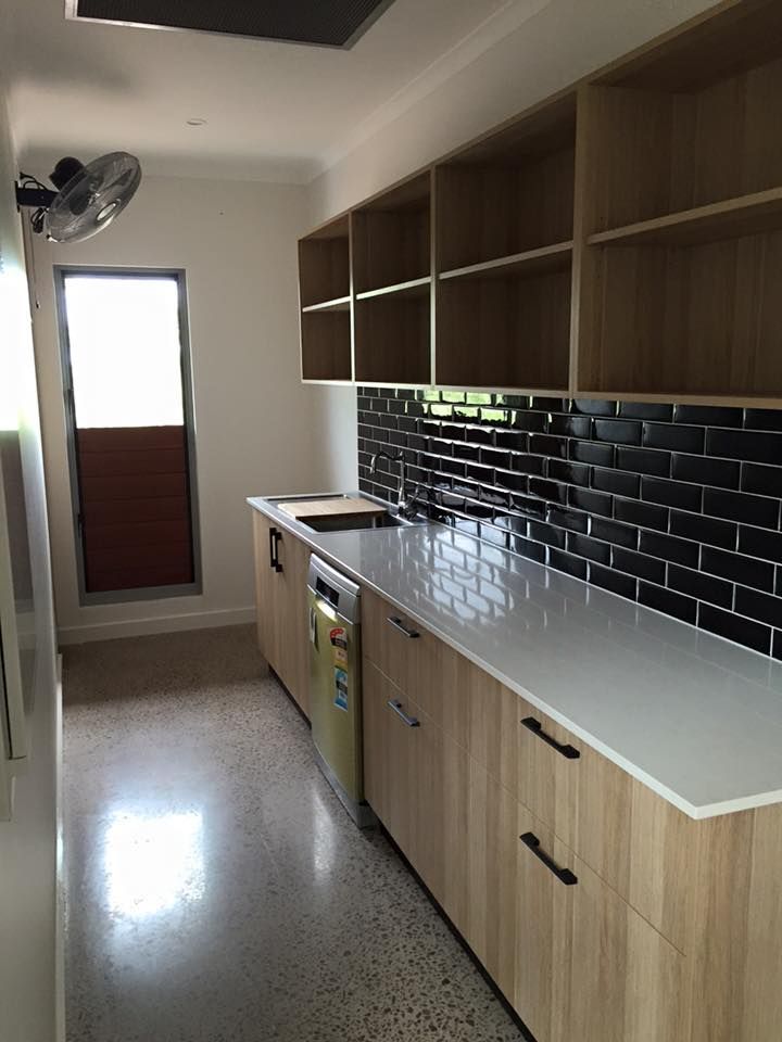 A Kitchen With Wooden Cabinets , White Counter Tops , And Black Brick Tiles — SLS Builders Pty Ltd in Humpty Doo, NT