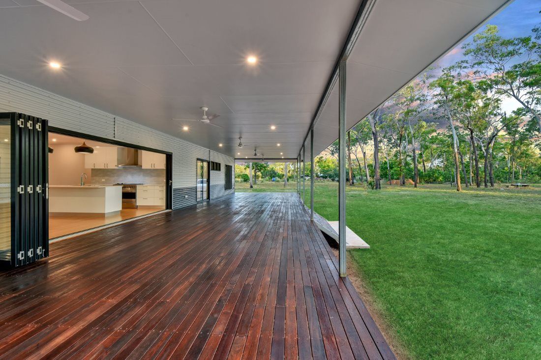 A Large Wooden Deck With A Sliding Glass Door Leading To A Kitchen — SLS Builders Pty Ltd in Humpty Doo, NT