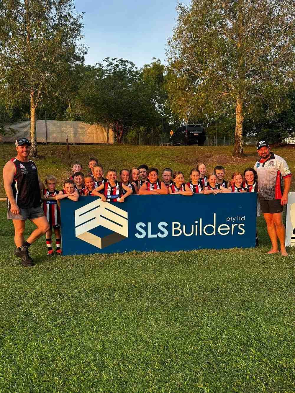 A Group Of People Standing In Front Of A Sign That Says Builders — SLS Builders Pty Ltd in Humpty Doo, NT