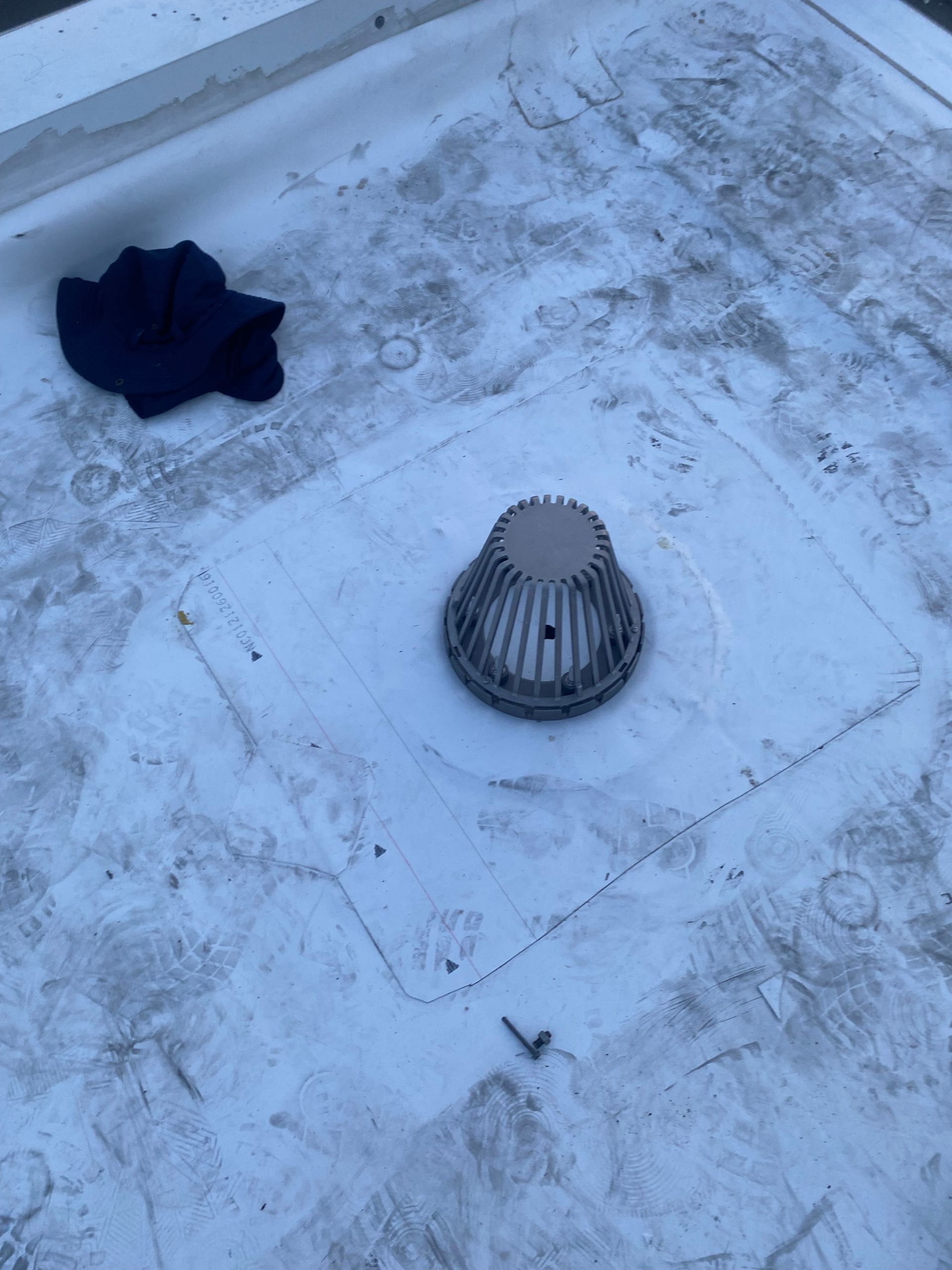 Snow-covered rooftop with a vent cap and a dark cloth lying nearby