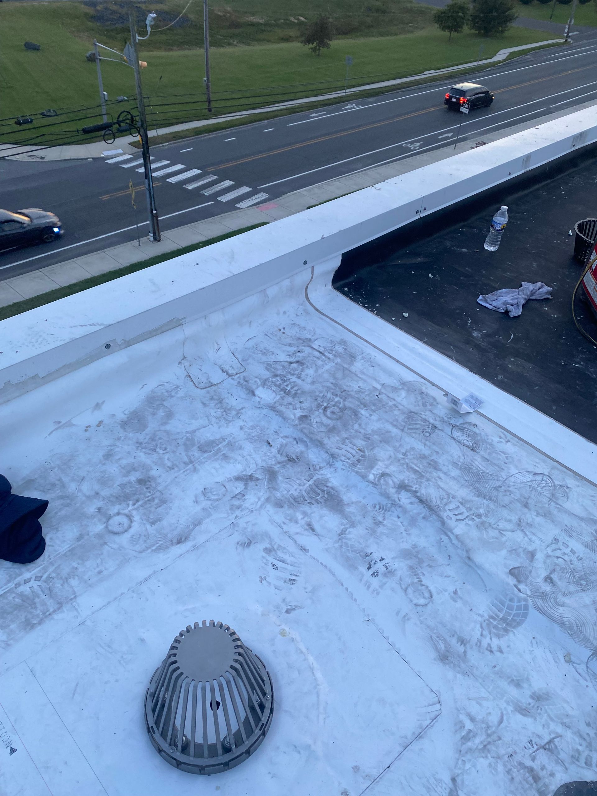 Snow-dusted rooftop with a vent in foreground, road and cars visible below.