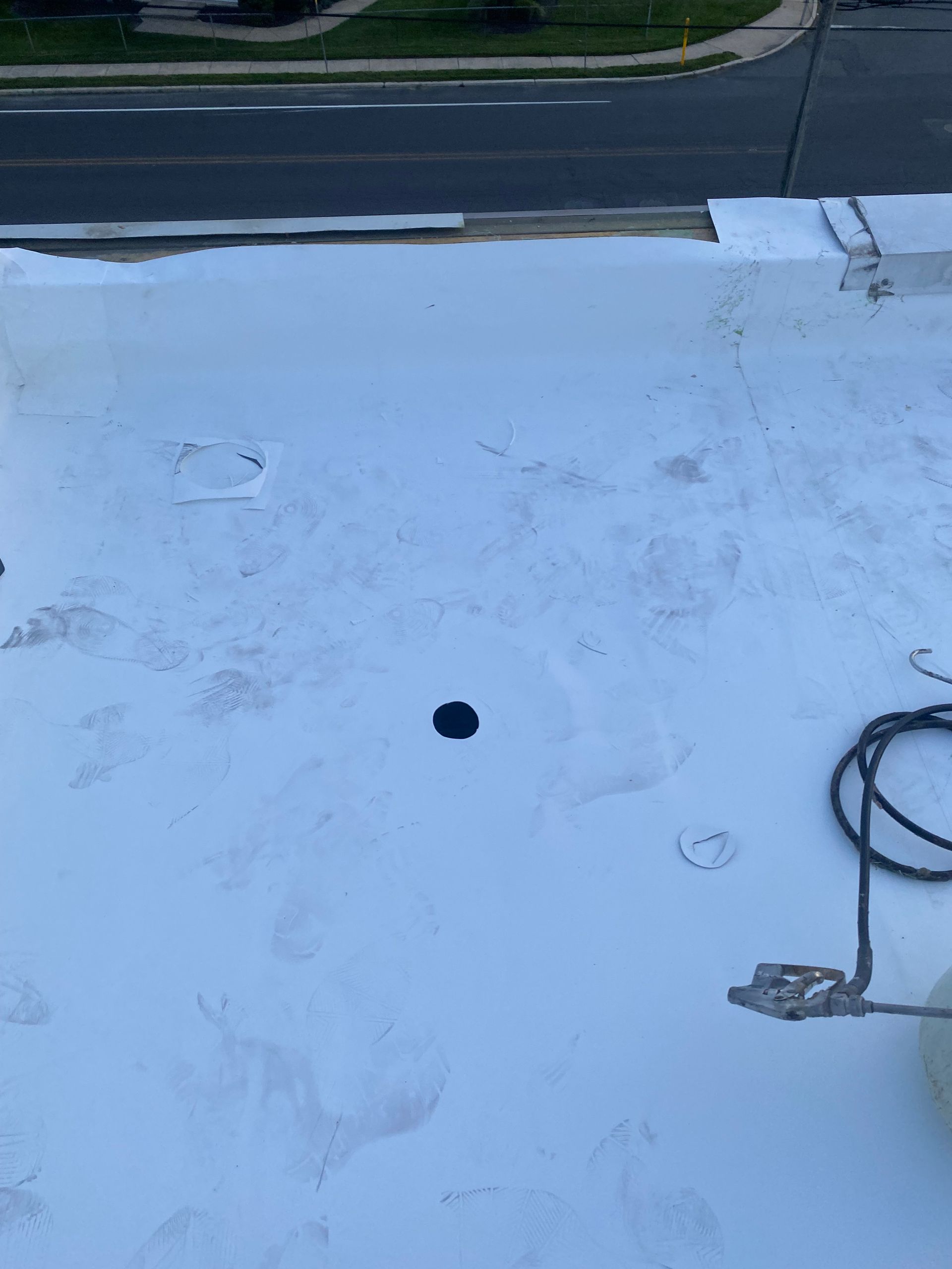 Flat white rooftop with a small black vent hole and a coiled cable on the right near the edge.