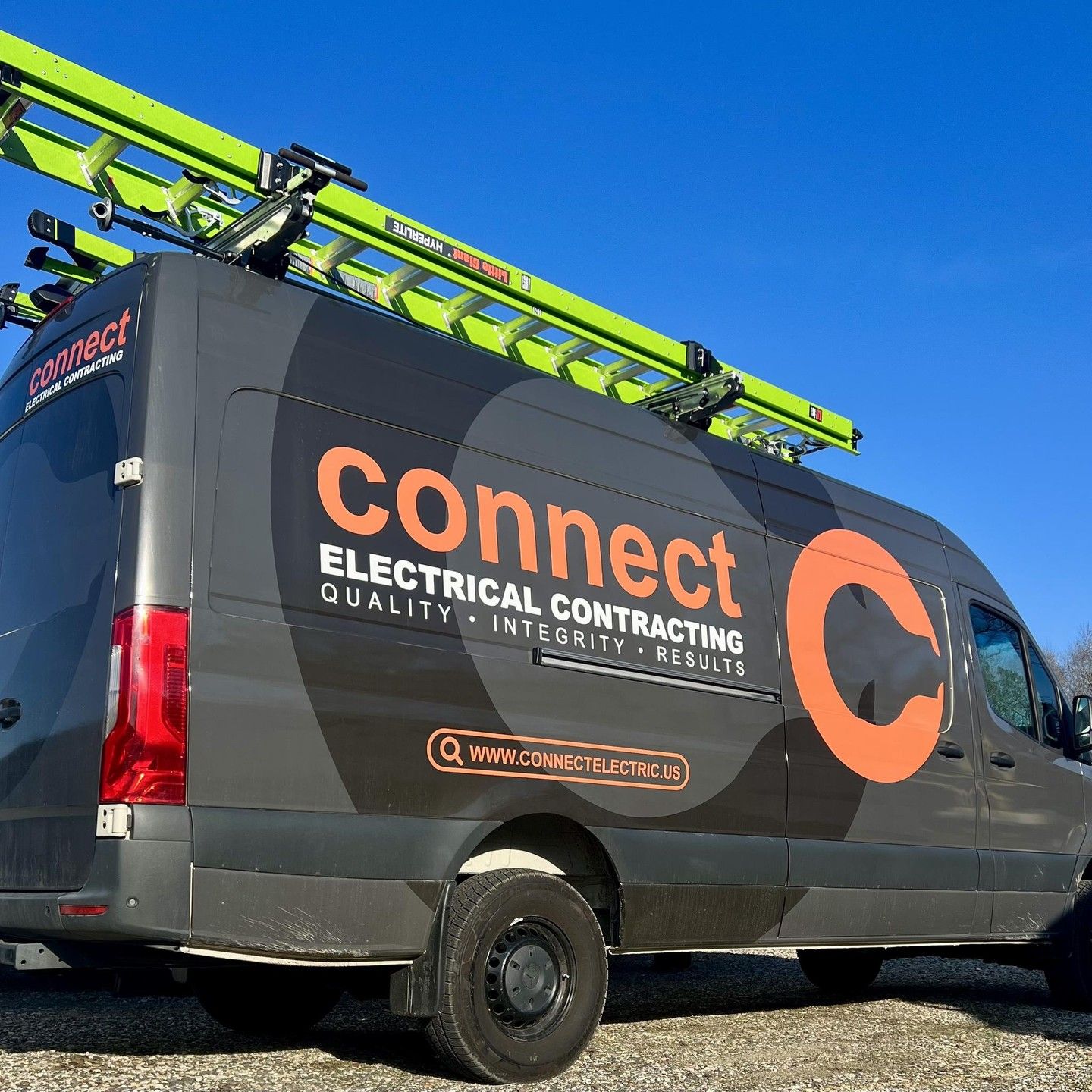 Gray Connect Electrical Contracting van with orange logo and green ladder on roof.