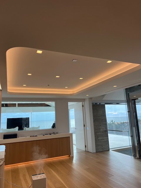Modern interior with a recessed, illuminated ceiling, wooden floors, and a reception desk.