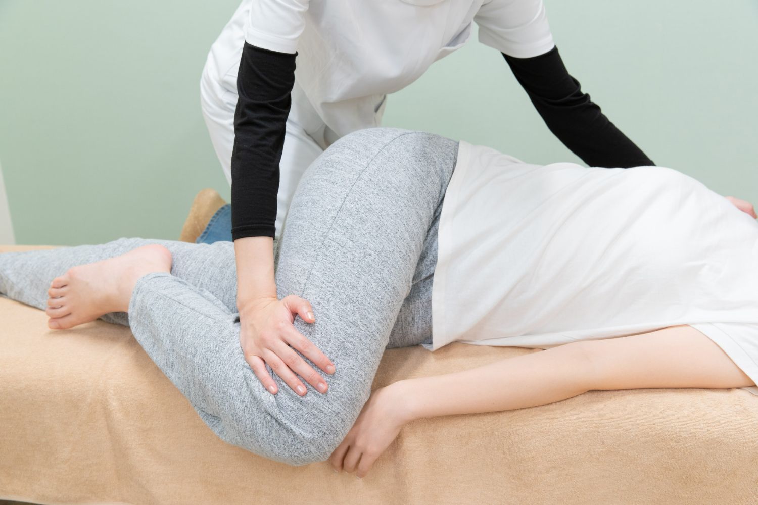 Physical therapist assisting a patient in a side-lying stretch on a treatment table