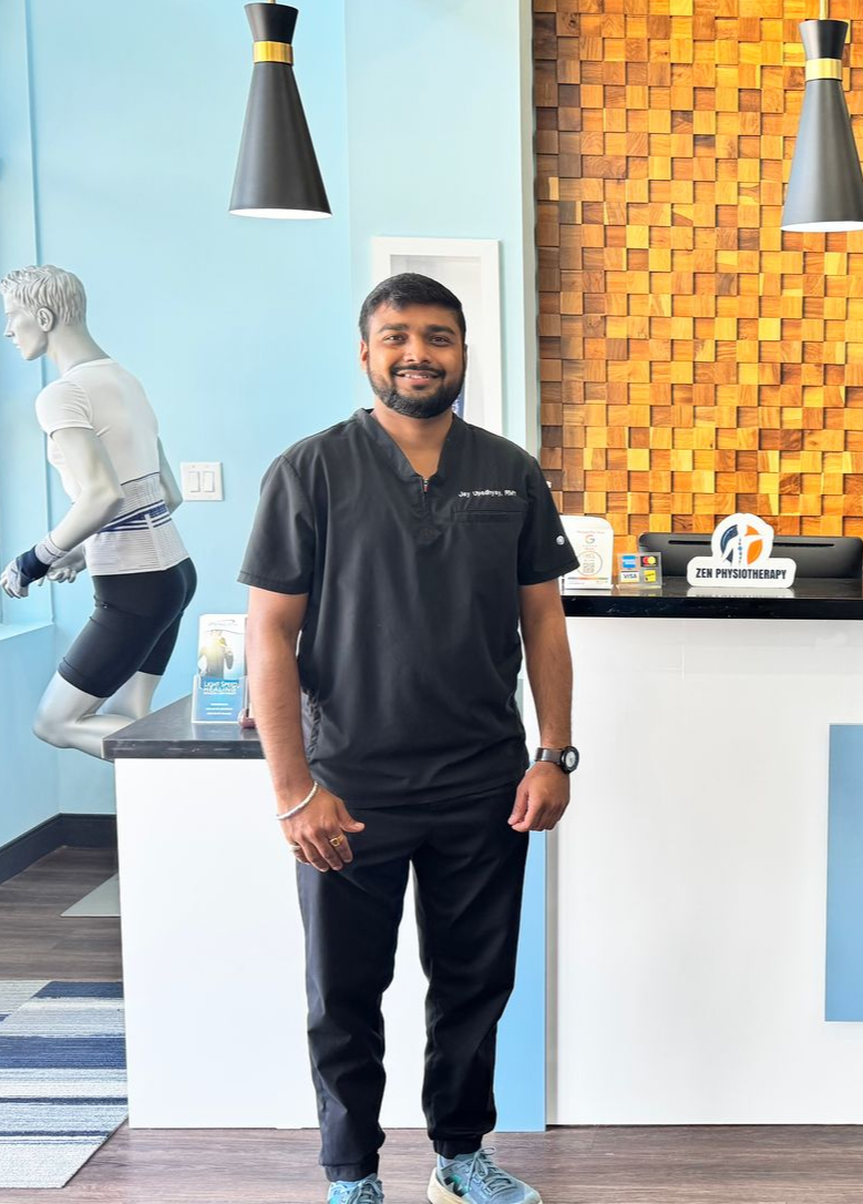 Person in teal medical scrubs stands with arms crossed against a plain light background.