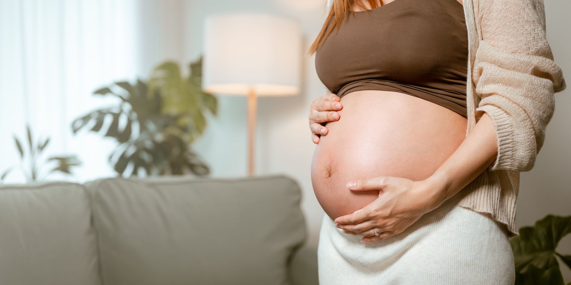 A pregnant woman is kneeling on a yoga mat while a woman helps her.