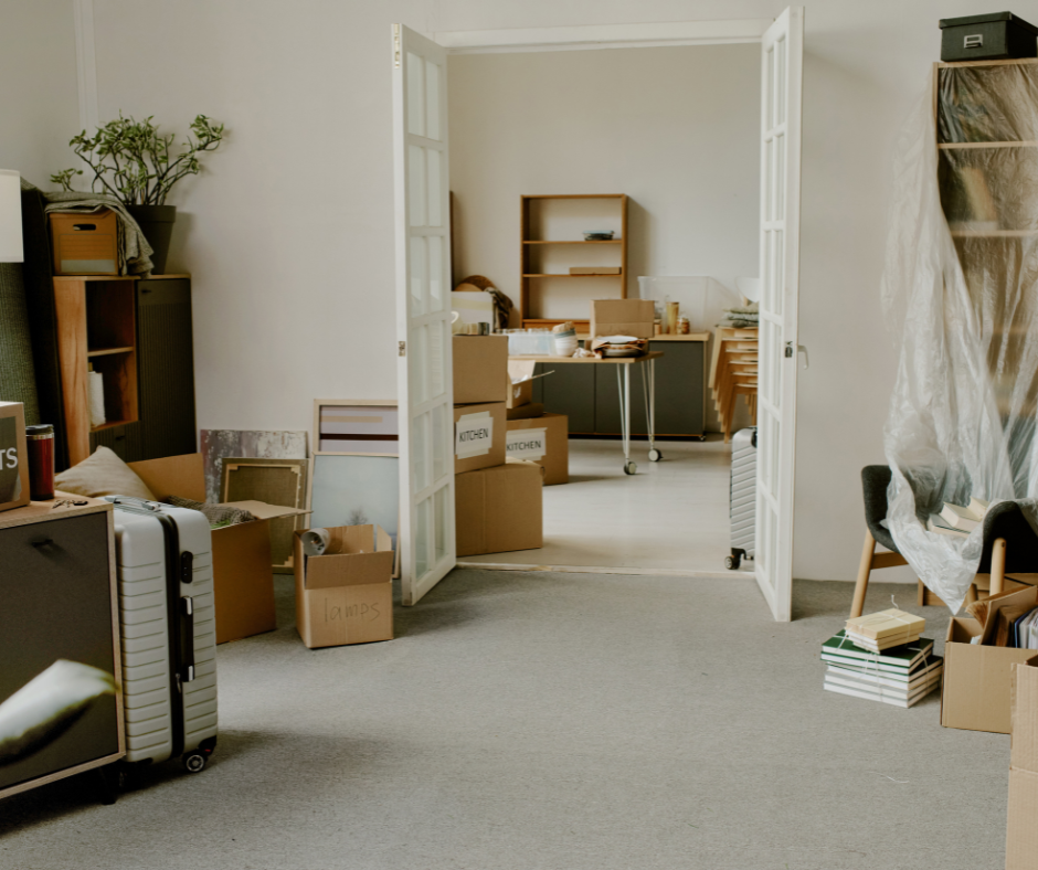 Messy room with moving boxes, shelves, and open double doors into an adjacent room