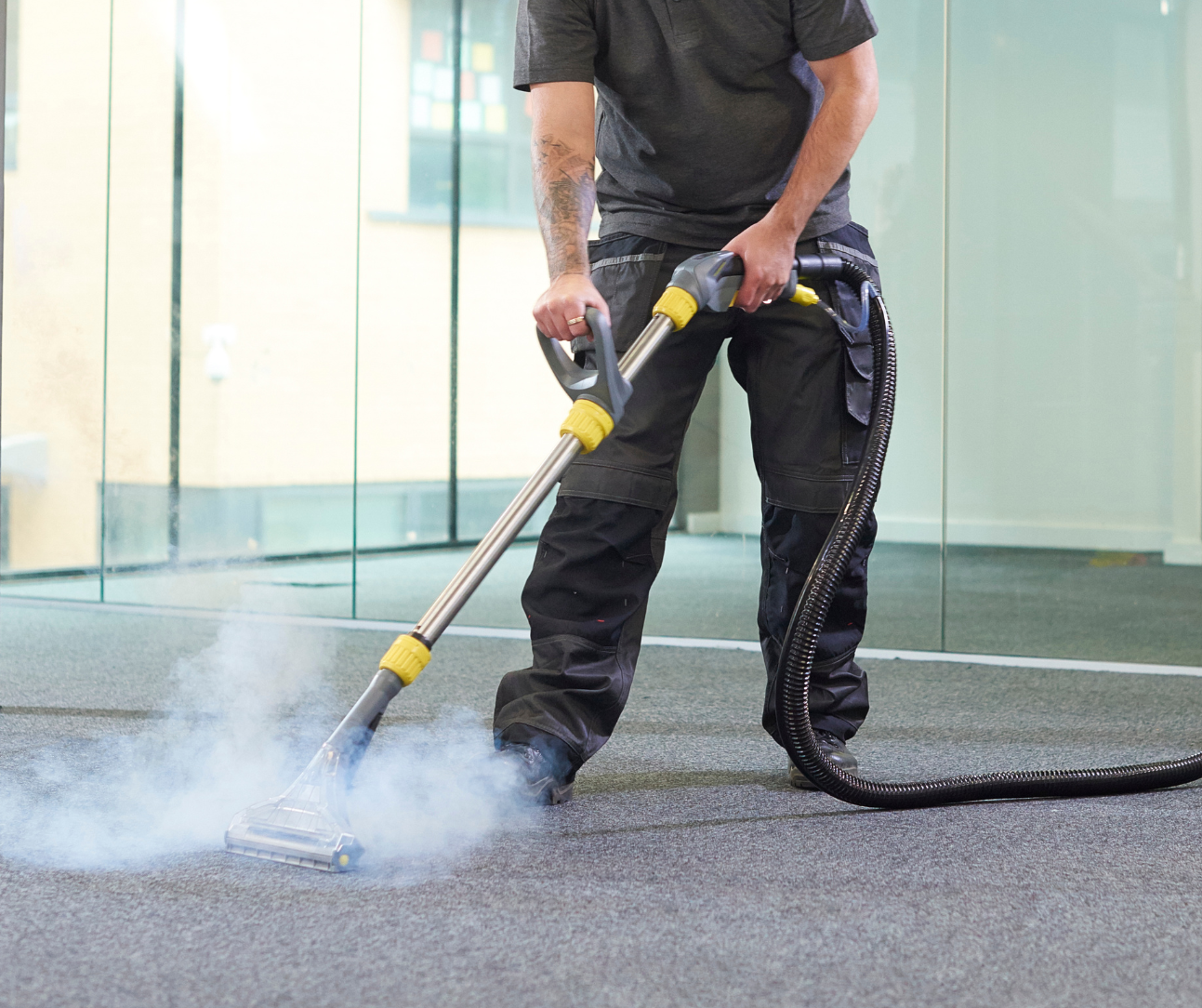 Worker cleaning carpet with steam vacuum in a bright indoor office space Worker cleaning carpet with steam vacuum in a bright indoor office space